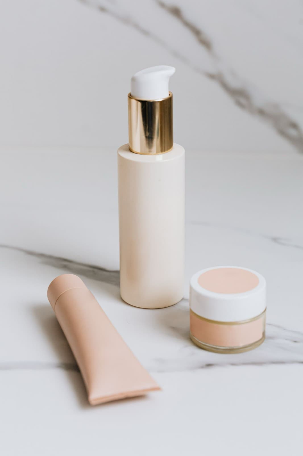 Skincare bottles and a cosmetic jar arranged on a marble surface