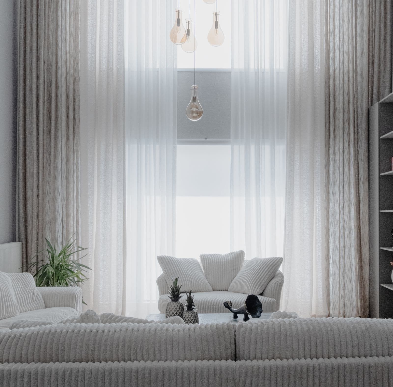 A bright living room with a sofa, armchair, and sheer curtains