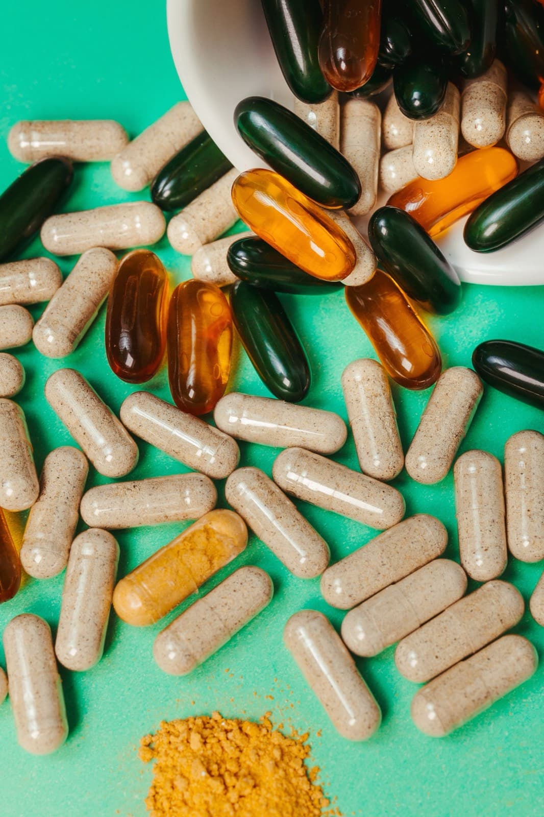 Capsules and supplement pills spilling from a white bowl
